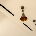 Frameless air-conditioning vents integrated into the ceiling beside hanging light fixtures.