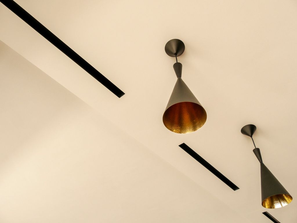Frameless air-conditioning vents integrated into the ceiling beside hanging light fixtures.